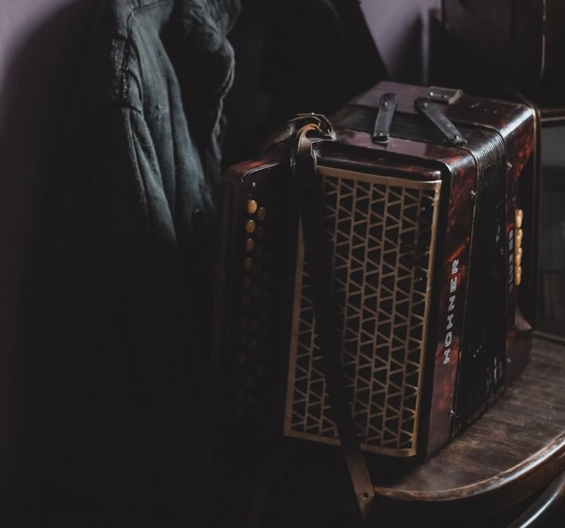 an old accordion sitting on a table next to a chair